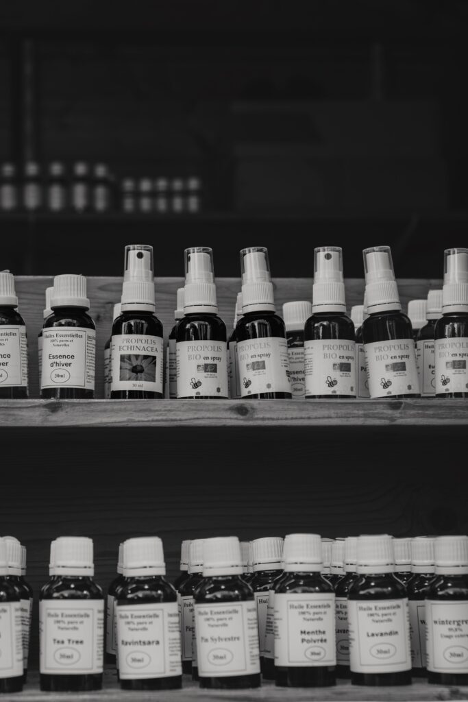 A black and white image of natural health products on wooden shelves at a market.